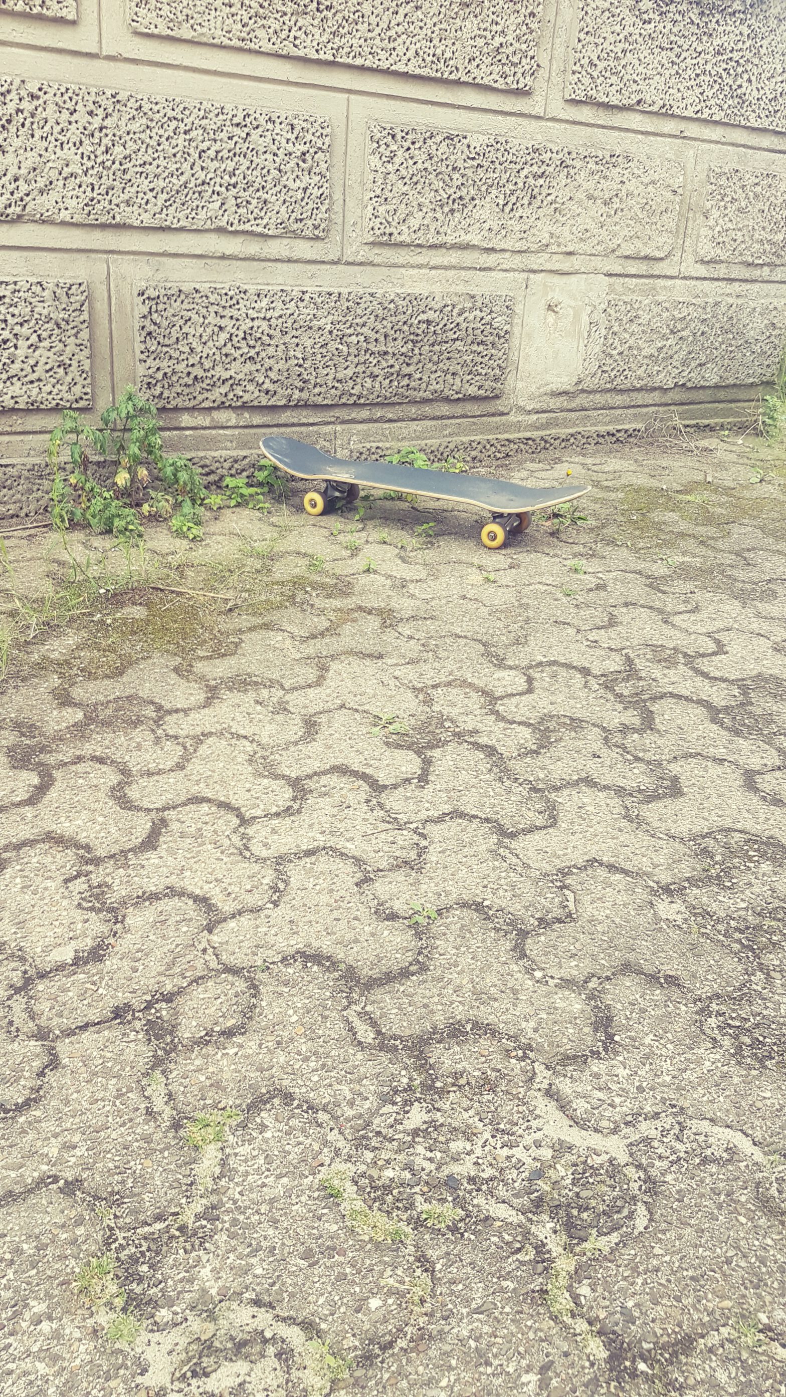 Skateboard auf Asphalt vor Häuserwand