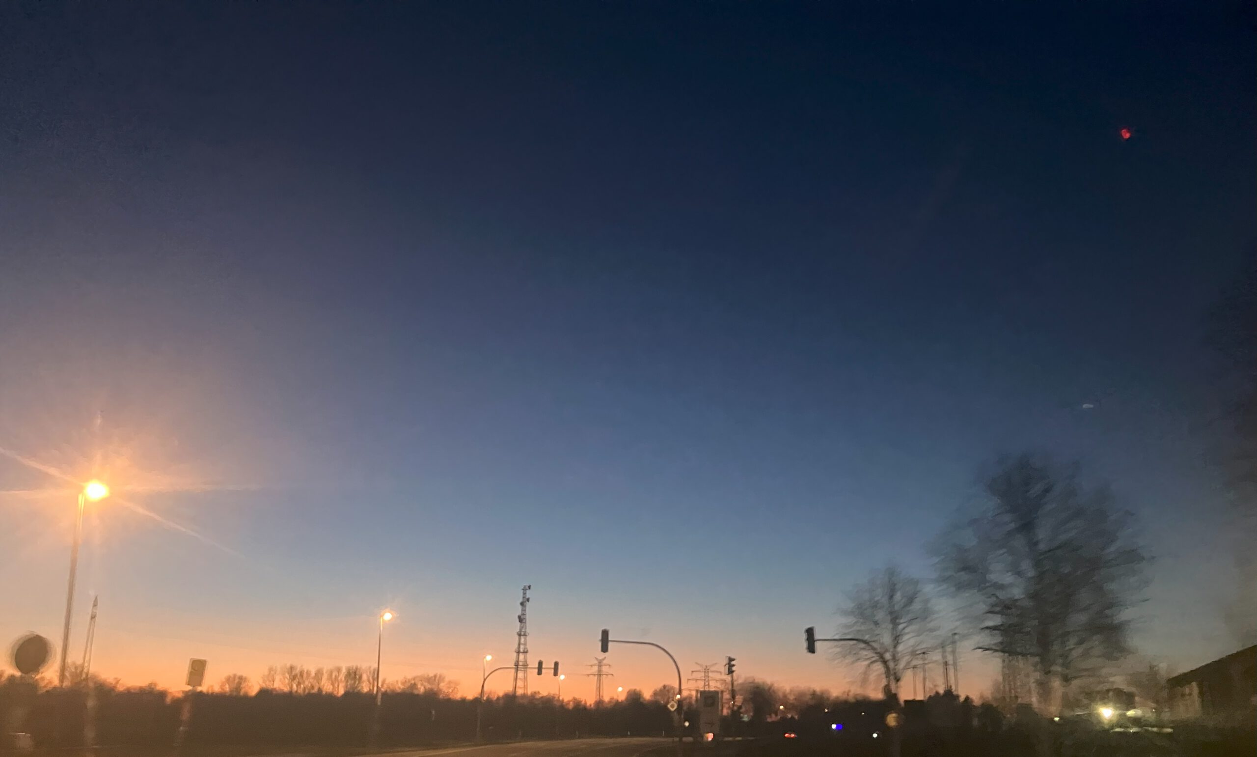 sonnenuntergang am Horizont, davor Ampeln, Stadtszene